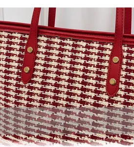 Detailed close-up of the red tweed weave fabric and golden metal rivets on the tote bag