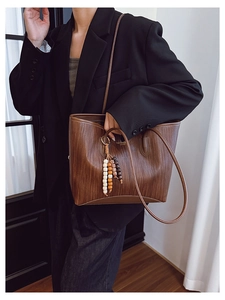 Brown woven tote bag detail featuring colorful wooden bead tassels and smooth PU leather texture