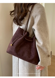 Deep brown suede tote bag with drawstring and gold metal sphere charm detail