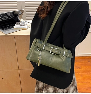 Detail of dark green vintage underarm bag with belt buckle and gold key charm