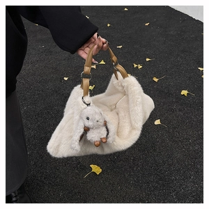 Dettaglio della borsa in peluche crema con manico in pelle e ciondolo a coniglio