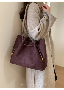 Detail of vintage retro tote bag in burgundy suede with elegant gold ball hardware accents