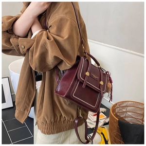 Detail of burgundy vintage backpack with contrast stitching and leather brand tag