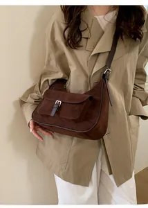 Side view of dark brown suede saddle bag on model wearing a beige trench coat