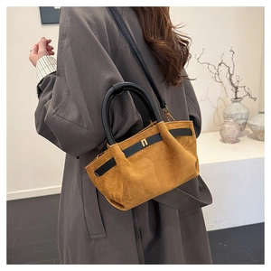 Detail of tan suede tote with black circular handle and minimalist gold hardware buckle