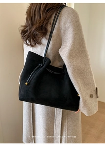 Detail of a retro suede tote bag with leather drawstring and elegant gold metal beads