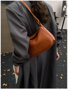 Close-up of vintage brown leather shoulder bag with buckle detail and embossed logo