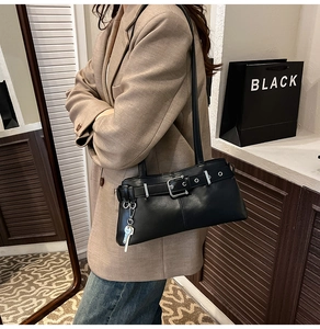Detail of black vintage shoulder bag with silver buckles and a key-shaped pendant accent