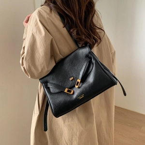 Detail of black PU leather tote bag with gold buckle hardware and brand logo