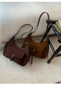Detailed view of suede shoulder bags in dark brown and caramel on beige carpet