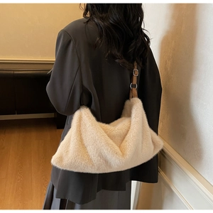 Détail d'un sac hobo en fausse fourrure beige avec bandoulière réglable en cuir marron