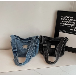 Detail view of retro denim shoulder bags in blue and black with adjustable straps