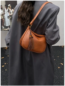 Close-up of brown textured leather hobo bag with wooden bead tassels and shoulder strap