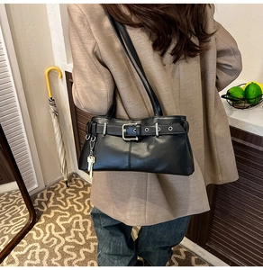 Detail view of black vintage underarm bag featuring decorative strap and silver buckle