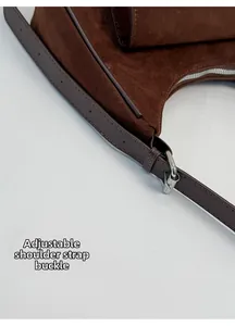 Detail of dark brown tote bag showing adjustable leather shoulder strap with silver buckle