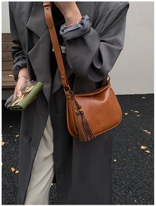 Close-up of vintage brown leather pillow bag with long tassel and wooden bead detail