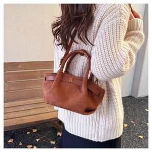 Brown frosted suede tote bag with golden clasp worn on shoulder in autumn park setting