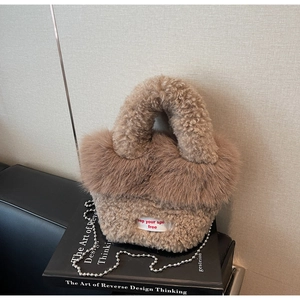 Détail du sac seau en peluche avec textures en fausse fourrure et étiquette en tissu