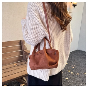 Detail of a matte dark brown crossbody bag on a model in an autumn outdoor setting