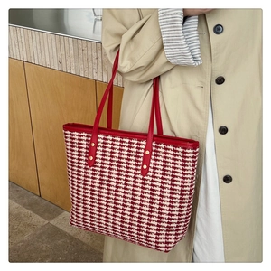 Detail of red houndstooth tote bag with leather handles and gold rivet accents