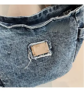 Close-up of vintage washed blue denim fabric with polished rectangular metal brand plate