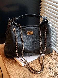 Classic black quilted shoulder bag with gold chain strap on a wooden surface