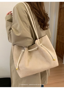 Detail of beige suede tote bag with woven rope handle and metallic sphere ornament