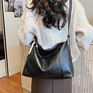 Detail of black pebbled leather hobo bag with designer beads on model in white sweater