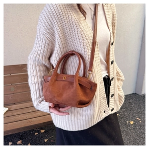 Brown matte tote bag with crossbody strap and metal buckle in an autumn fashion setting