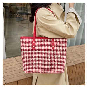 Detail of red and white houndstooth tote bag with gold studs and red leather strap