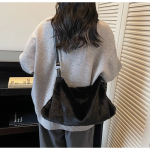 Grand sac cabas noir en fausse fourrure avec bandoulière en cuir porté par un modèle