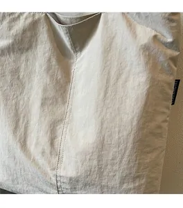 Détail du sac fourre-tout beige avec tissu en nylon texturé et étiquette latérale tissée