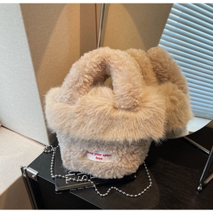 Détail du sac seau beige en fausse fourrure avec étiquette brodée et bandoulière chaîne