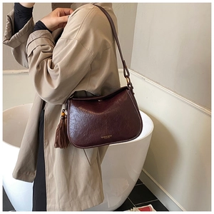 Detail of dark burgundy faux leather shoulder bag with side tassel and printed logo