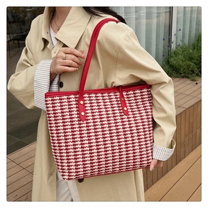 Detail of red houndstooth tote bag with gold rivets and leather shoulder straps