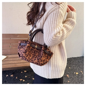 Detail of leopard print handbag with plush texture and brown leather strap in autumn park