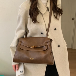 Detail showing vintage brown leather shoulder bag with gold twist lock and brand logo