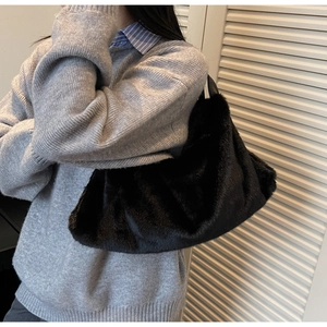 Détail de la texture douce du sac bandoulière en peluche noire porté par le modèle