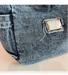 Detail of vintage washed denim fabric with metallic tag and retro frayed edges
