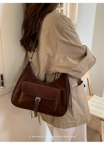 Brown retro suede shoulder bag with buckle detail shown on model in minimalist interior