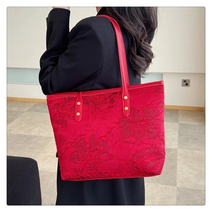 Detailed view of red jacquard tote bag with floral patterns and gold metal rivets