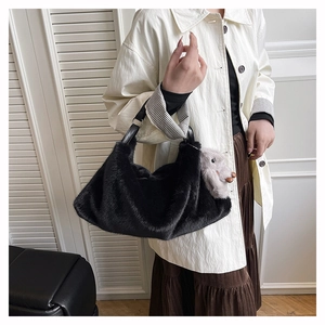 Dettaglio borsa tote in peluche nera con ciondolo a cucciolo grigio e manico in pelle