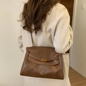 Detail of vintage brown leather shoulder bag with metallic twist lock and logo texture