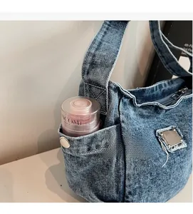 Detail of a denim shoulder bag side pocket with a silver button for storage