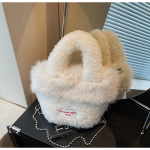 Détail du sac à main en fausse fourrure blanche avec étiquette et chaîne à boules