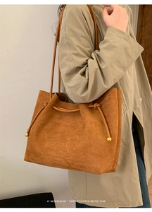 Detail of retro brown suede tote bag with drawstring closure and gold metal accents