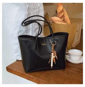 Detail of black woven tote bag with vintage wood bead tassel and gold lettering