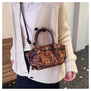 Detail of leopard print handbag with leather handle and gold hardware in autumn setting
