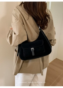 Detailed view of retro black suede underarm bag with silver buckle on a stylish model