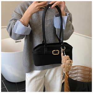 Details der schwarzen Vintage-Matte-Schultertasche mit goldener Schnalle und Bär-Anhänger